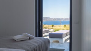 Un dormitorio con cama, un par de toallas y vistas al mar y a las montañas.