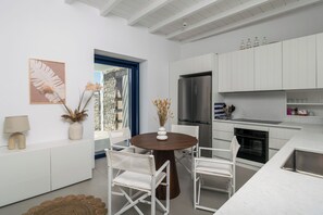 A modern kitchen with white cabinetry, a stainless steel refrigerator, and a round wooden table with chairs. - Villa Nabia II, Seaview and Sunset view, Private Pool (Adamas)