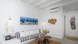 Una sala de estar moderna con un sofá blanco, una mesa de centro, un cuadro y un espejo.