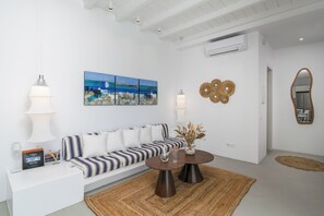 Una sala de estar moderna con un sofá blanco, una mesa de centro, un cuadro y un espejo.