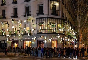 Un edificio con varias fachadas de tiendas, cada una con letreros iluminados.