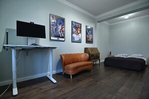 Une pièce équipée d’un téléviseur à écran plat, d’un canapé en cuir marron, d’un lit et de plusieurs affiches de films accrochées au mur.