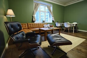Une pièce comprenant un canapé en cuir marron, un fauteuil en cuir noir, une table basse en bois et une petite table avec des chaises.