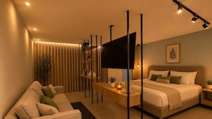 A modern bedroom with a sofa, a bed, a TV, and a bedside table. - Apartamentos HEM (Medellín)