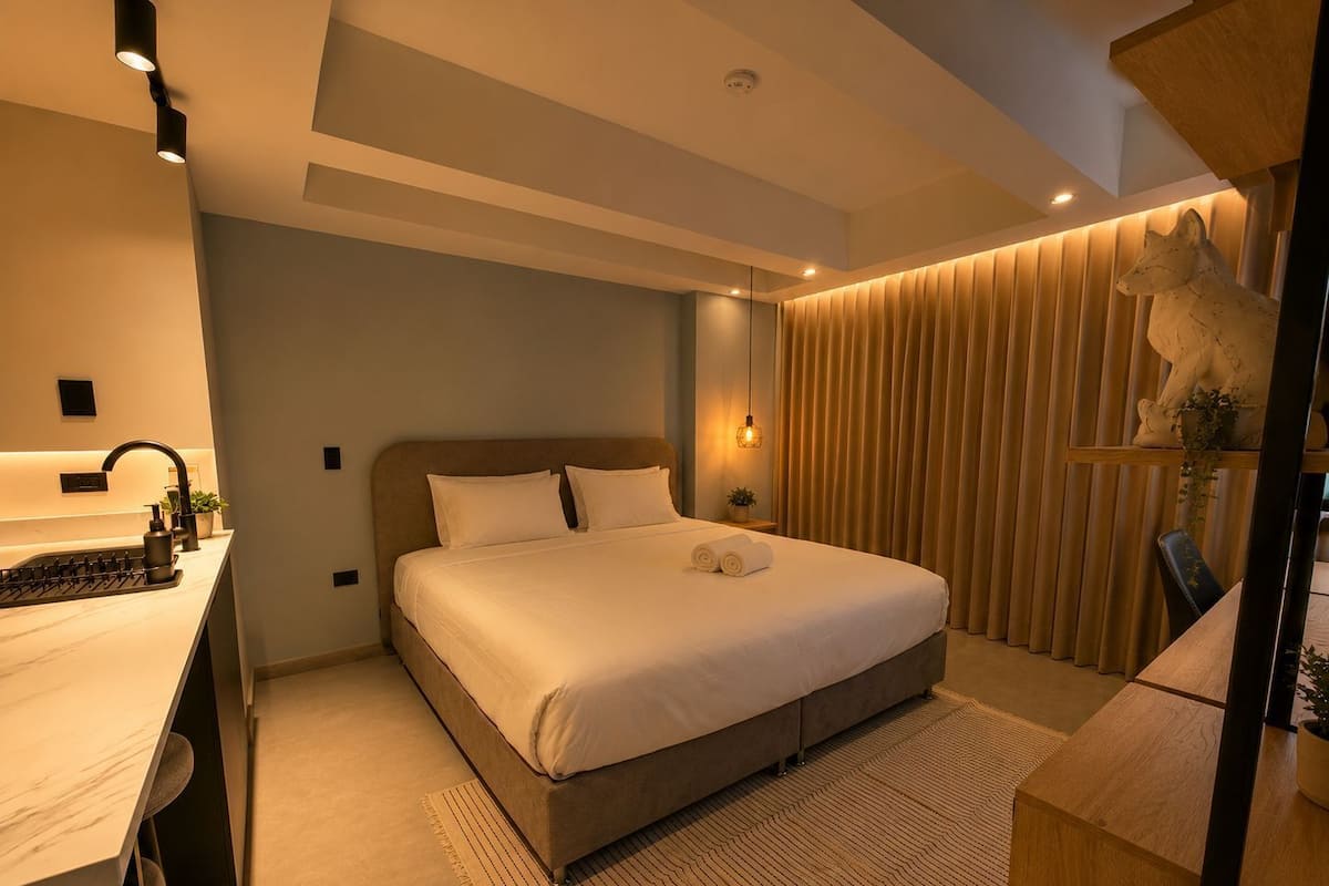 A modern bedroom with a large bed, a desk with a sink, and a decorative fox sculpture.