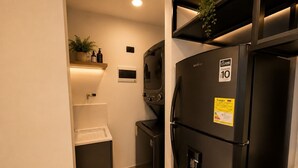 A compact kitchen with a black refrigerator, a small sink, and a shelf with toiletries. - Apartamentos HEM (Medellín)