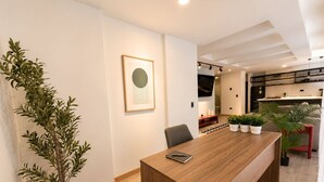 A modern kitchen with a wooden countertop, a dining area with a wooden table, and a potted plant. - Apartamentos HEM (Medellín)