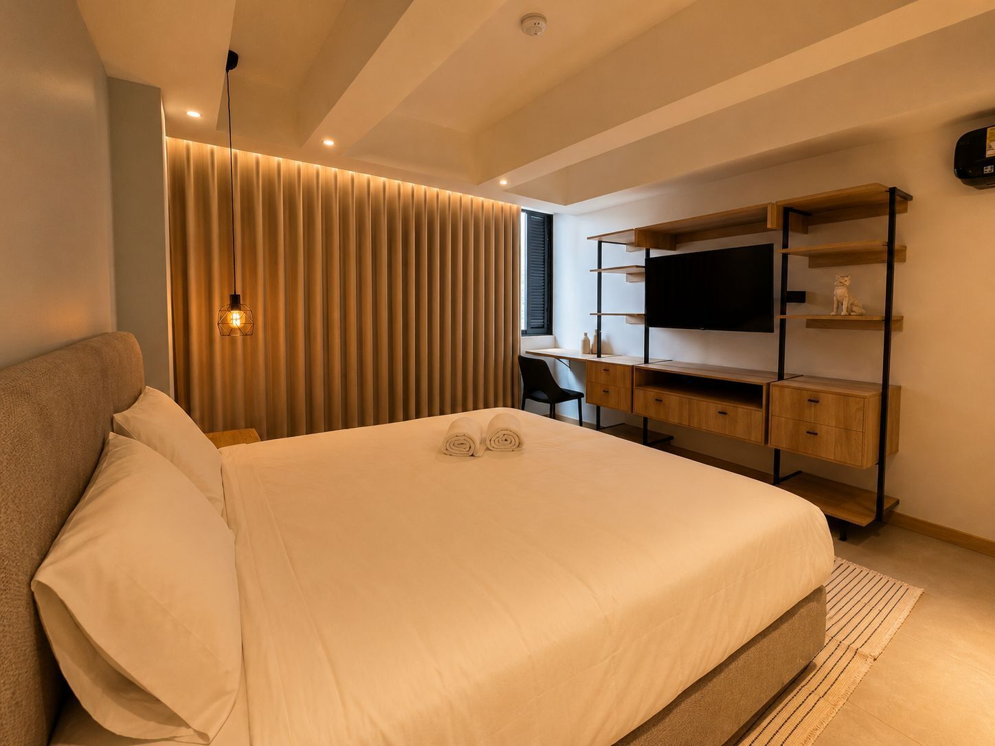 Un dormitorio moderno con cama, escritorio y televisor.