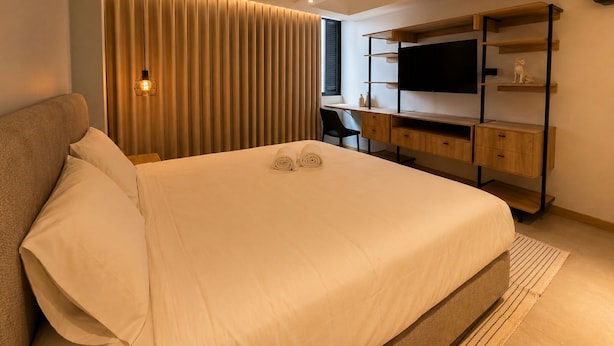 A modern bedroom with a bed, desk, and TV. - Apartamentos HEM (Medellín)