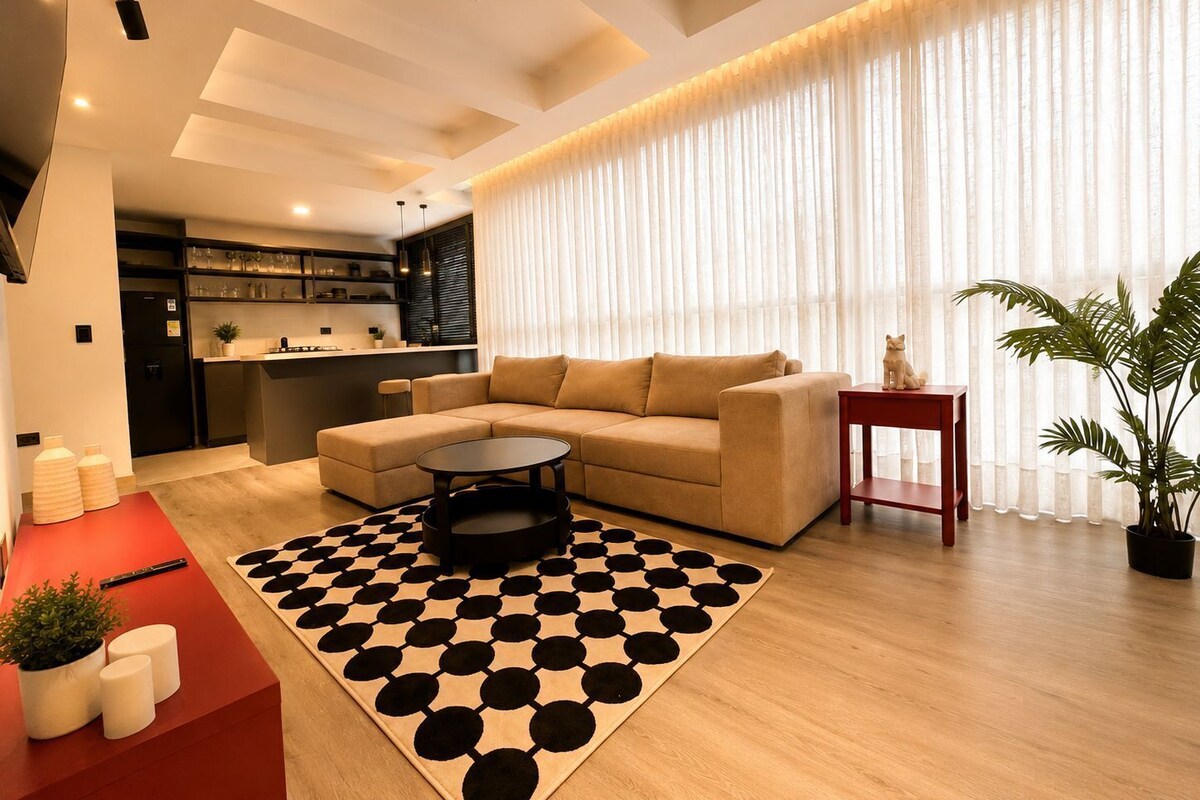 A modern living room with a sofa, coffee table, and a patterned rug.