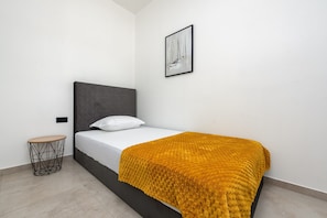 Ein modernes Schlafzimmer mit einem Bett, einem runden Beistelltisch, einem gerahmten Bild an der Wand und einer strukturierten Decke.