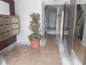 Ein Flur mit einem Blumentopf, einer Holzkommode mit mehreren Fächern und einer Treppe, die in einen weiteren Bereich führt.