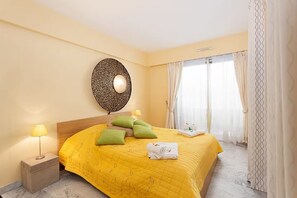 Ein Hotelzimmer mit Bett, Kissen, einer Nachttischlampe, einer Wanddekoration und einem Fenster mit Vorhängen.
