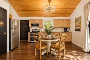 A kitchen with wooden cabinets, a stainless steel refrigerator, a dining table with chairs, and a chandelier. - Jeep Friendly Smoky Mountain Cabin with Views (Sevierville)