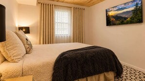 Une chambre à coucher avec un lit, des rideaux, un tableau et un plafond en bois.
