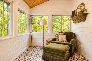 A room with a green sofa, a lamp, and a decorative shelf with a mirror and a deer statue. - Jeep Friendly Smoky Mountain Cabin with Views (Sevierville)