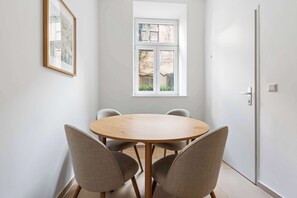 A room with a round wooden table, four chairs, a window, and a door. - Design 3BR Apartment | Comfort | Kitchen | Central (Wien)