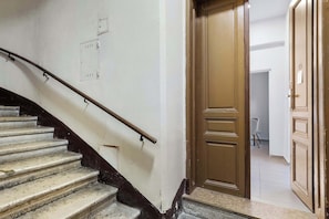 Un escalier avec une rampe, une porte en bois et un mur blanc équipé de prises électriques.