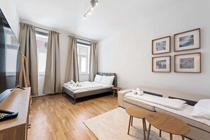 Ein modernes Hotelzimmer mit Bett, Sofa, Fernseher und Bildern an der Wand.