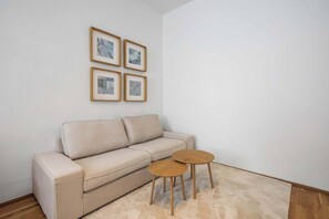 A beige sofa, two small wooden tables, and four framed pictures on the wall. - Design 3BR Apartment | Comfort | Kitchen | Central (Wien)