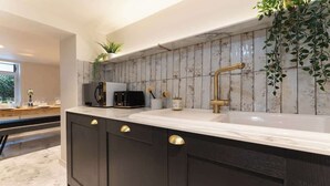 Une cuisine moderne avec des meubles de couleur sombre, un plan de travail blanc et un grand évier.