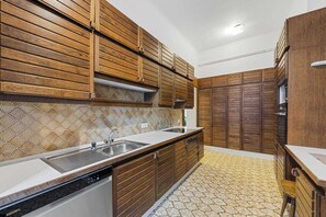 A kitchen with wooden cabinets, a stainless steel sink, and a patterned floor. - Stylish 3BR Apt. | Central | Kitchen | Balcony (Wien)