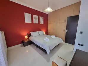 Ein Schlafzimmer mit Bett, Nachttischen, einem Kleiderschrank und Wandbildern.