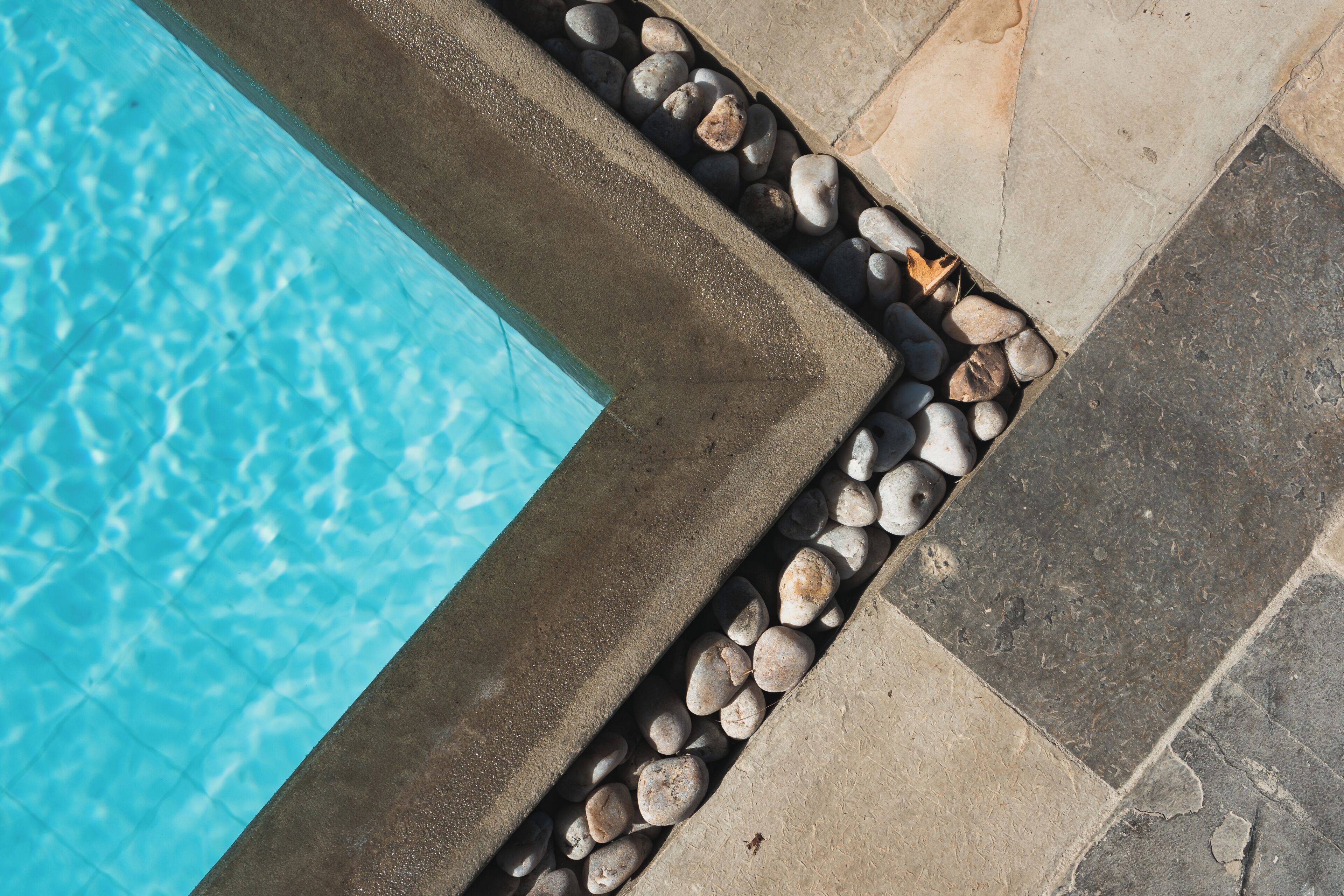 Una piscina de agua cristalina, rodeada por un borde de piedra con guijarros.