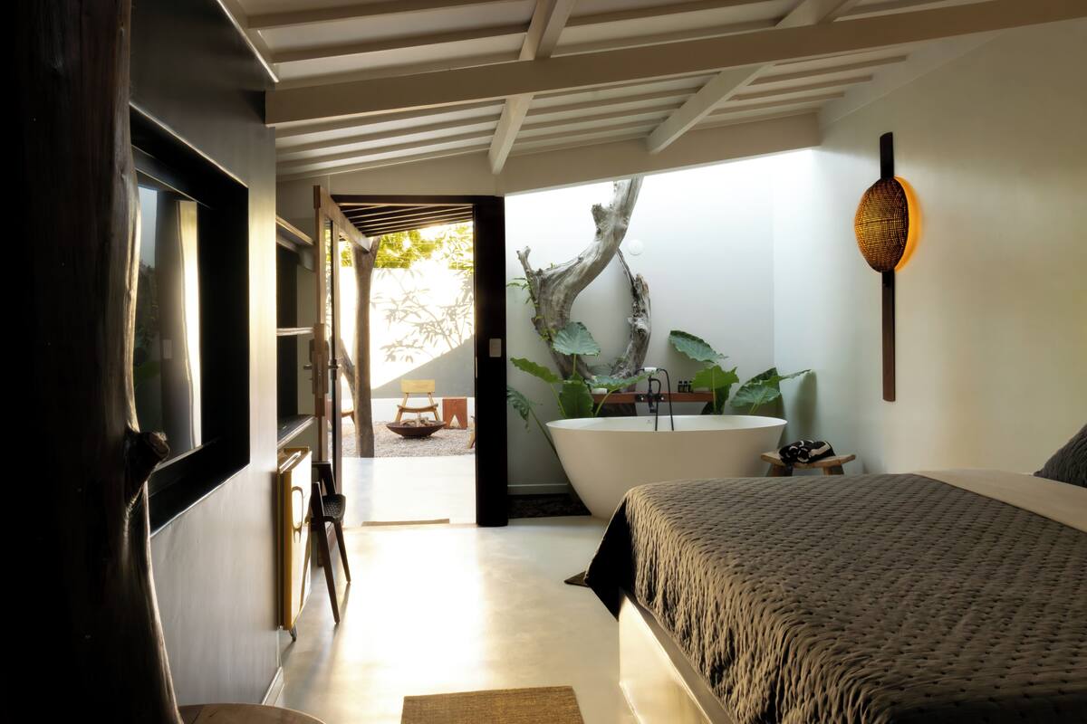 Un dormitorio moderno con una cama grande, una bañera y vistas a un jardín.