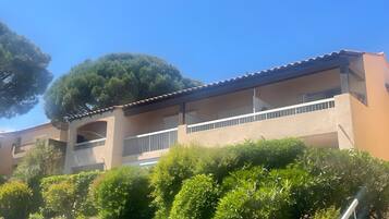 A multi-story building with balconies, surrounded by lush greenery.