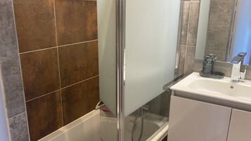A modern bathroom with a glass-enclosed shower, a white sink, and a mirror above it.
