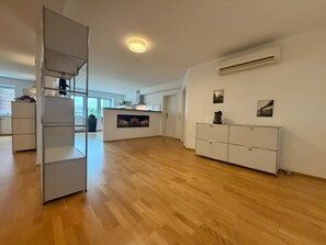 Une pièce spacieuse avec un plancher en bois, une armoire blanche, une étagère en métal et, au fond, un coin cuisine.