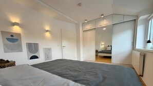 Une chambre moderne avec un grand lit, une armoire et un miroir.