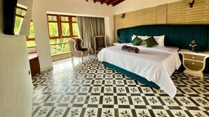 Ein Schlafzimmer mit Schachbrettboden, einem Bett mit grün-weißer Bettwäsche, einer Holzbalkendecke und einer Backsteinwand.