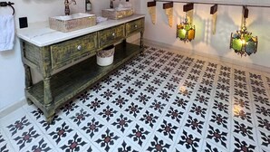 Ein Badezimmer mit einem Holzkosmetikschrank, zwei Spiegeln, einem Waschbecken und dekorativen Wandleuchten.