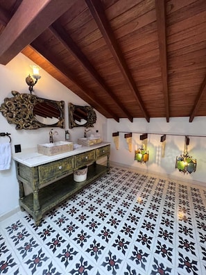 A bathroom with a wooden vanity, two mirrors, a sink, and decorative wall sconces.