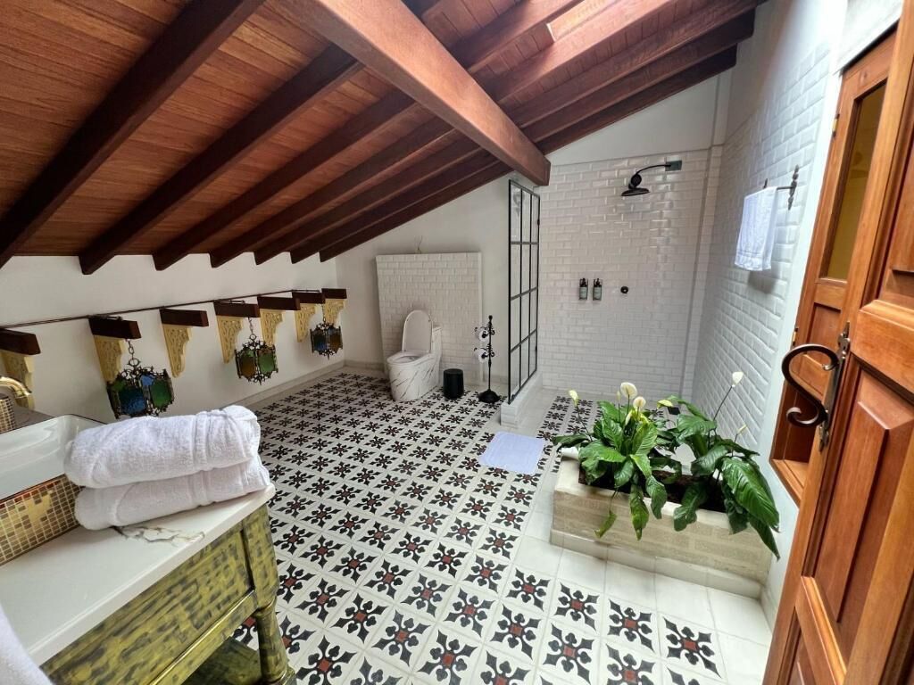 Een badkamer met betegelde vloer, een witte wastafel, een houten kast en een douchehoek.