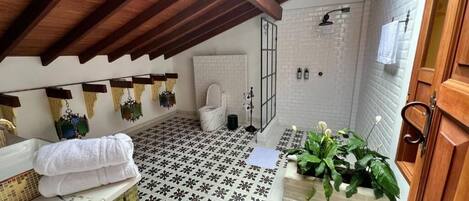 A bathroom with a tiled floor, a white sink, a wooden cabinet, and a shower area.