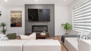 Ein modernes Wohnzimmer mit Flachbildfernseher, Kamin und zwei Sofas.