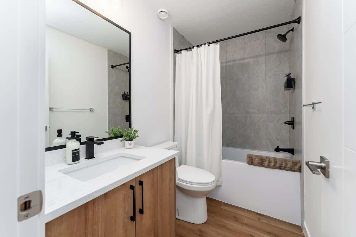 A modern bathroom with a shower, toilet, and sink.