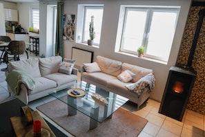 A living room with a sofa, a glass coffee table, a fireplace, and a kitchen in the background.