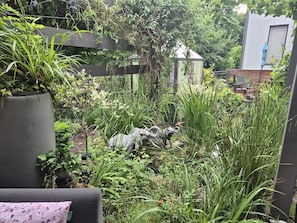 A lush garden with various plants and a small sculpture.