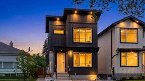A modern two-story house with large windows, a visible front door, and a small porch area. - 3BR Home Near Rogers Place & NAIT with Garage Parking (Edmonton)