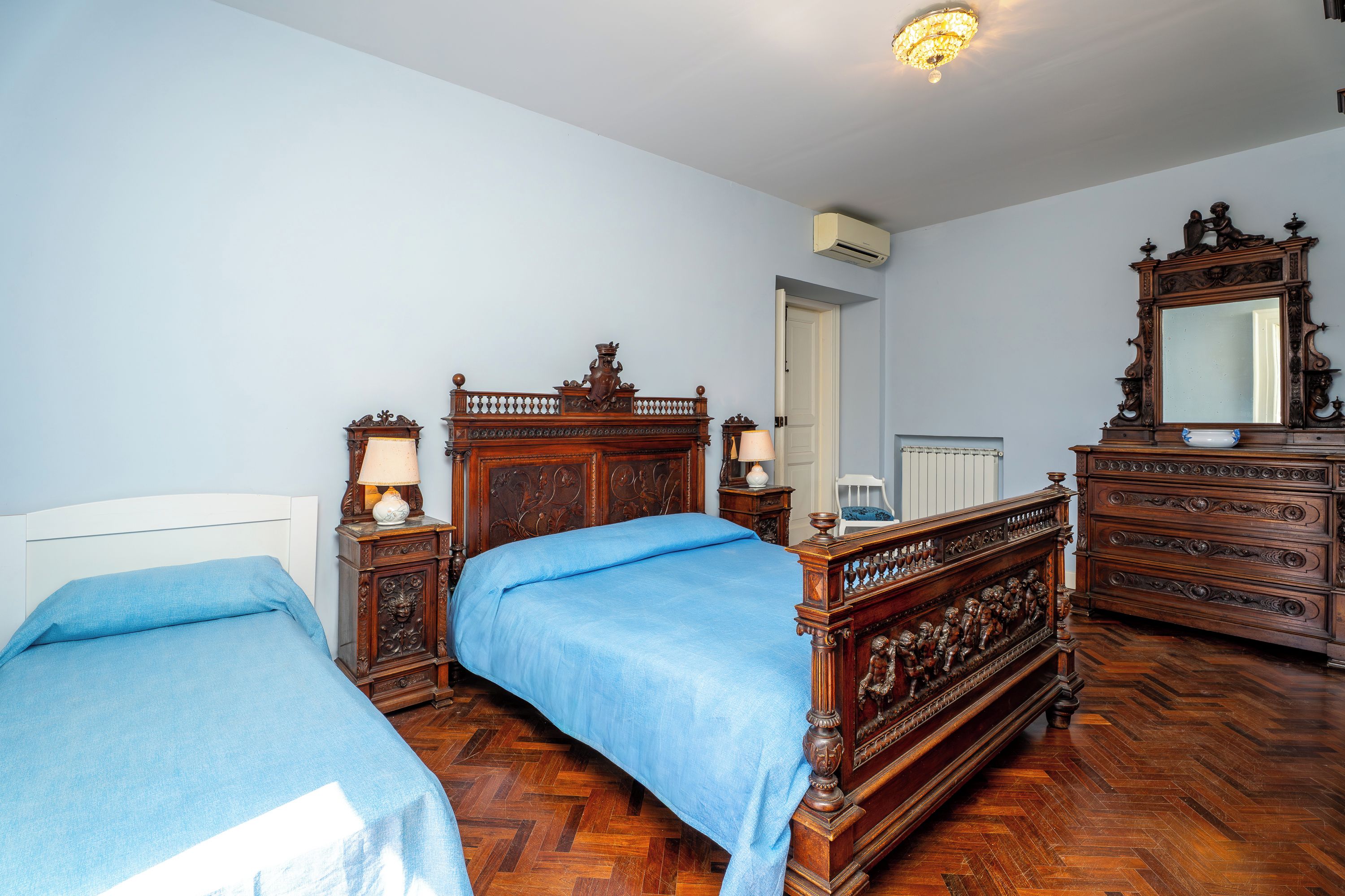 Quarto com duas camas, móveis de madeira e um espelho.