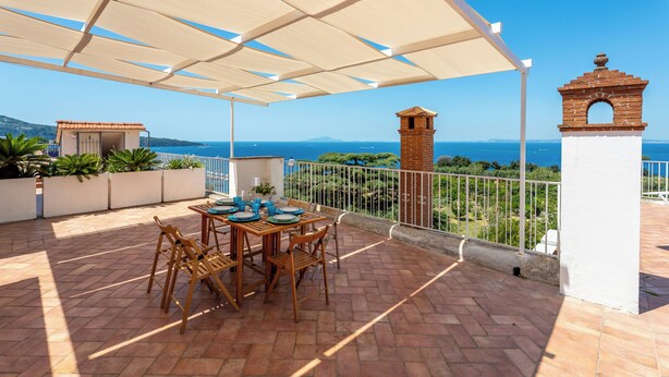 An outdoor patio with a table set for dining, overlooking a coastal view. - YourHome - La Terrazza nel Blu (Piano di Sorrento)
