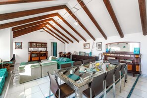 A spacious living area with a glass dining table, wooden beams, and a large mirror. - YourHome - La Terrazza nel Blu (Piano di Sorrento)