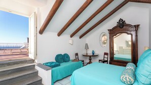 A bedroom with a bed, a chair, a table, and a staircase leading to an outdoor area. - YourHome - La Terrazza nel Blu (Piano di Sorrento)