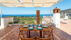 A terrace with a table set for dining, overlooking a coastal view. - YourHome - La Terrazza nel Blu (Piano di Sorrento)