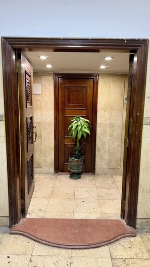 Una puerta de madera con una planta en maceta en el centro, un suelo de mármol y un felpudo marrón.