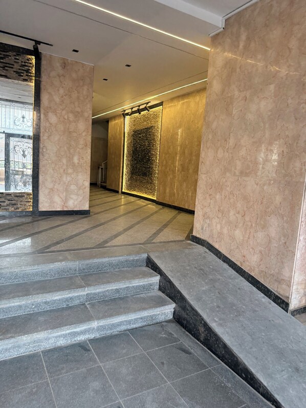 Un interior moderno con paredes de mármol, una escalera de piedra y una lámpara fijada a la pared.